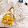 A yellow crocheted handbag and a white crocheted handbag with gold metal clasps displayed on a white fabric.