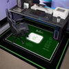 A black gaming area rug with a neon hexagon design and non-slip backing is displayed on a desk.