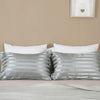 Silver and white striped pillow covers displayed on a bed with a neutral wall background.