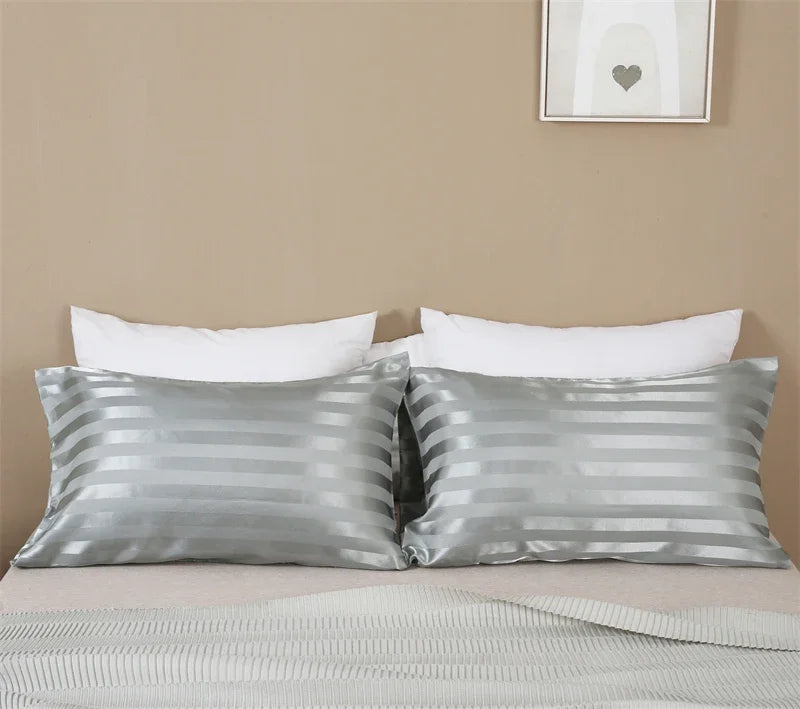 Silver and white striped pillow covers displayed on a bed with a neutral wall background.