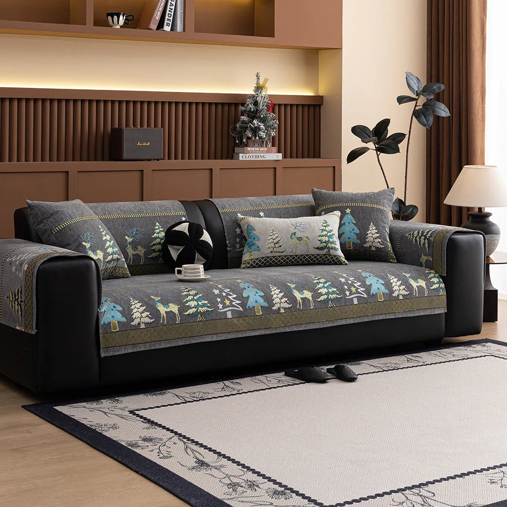 A dark gray sofa with a Christmas deer pattern mat cover and decorative pillows in a modern living room.
