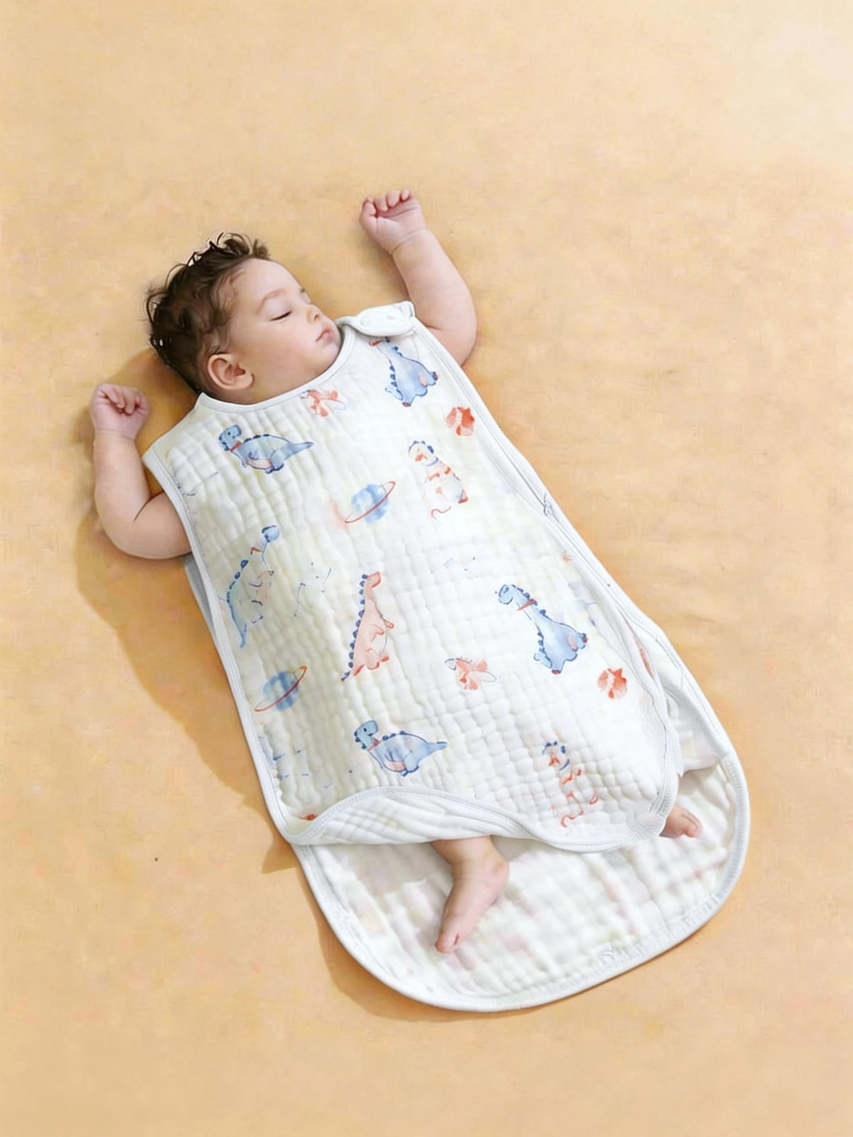 A baby is lying on a quilted white sleeping bag patterned with small birds and animals.