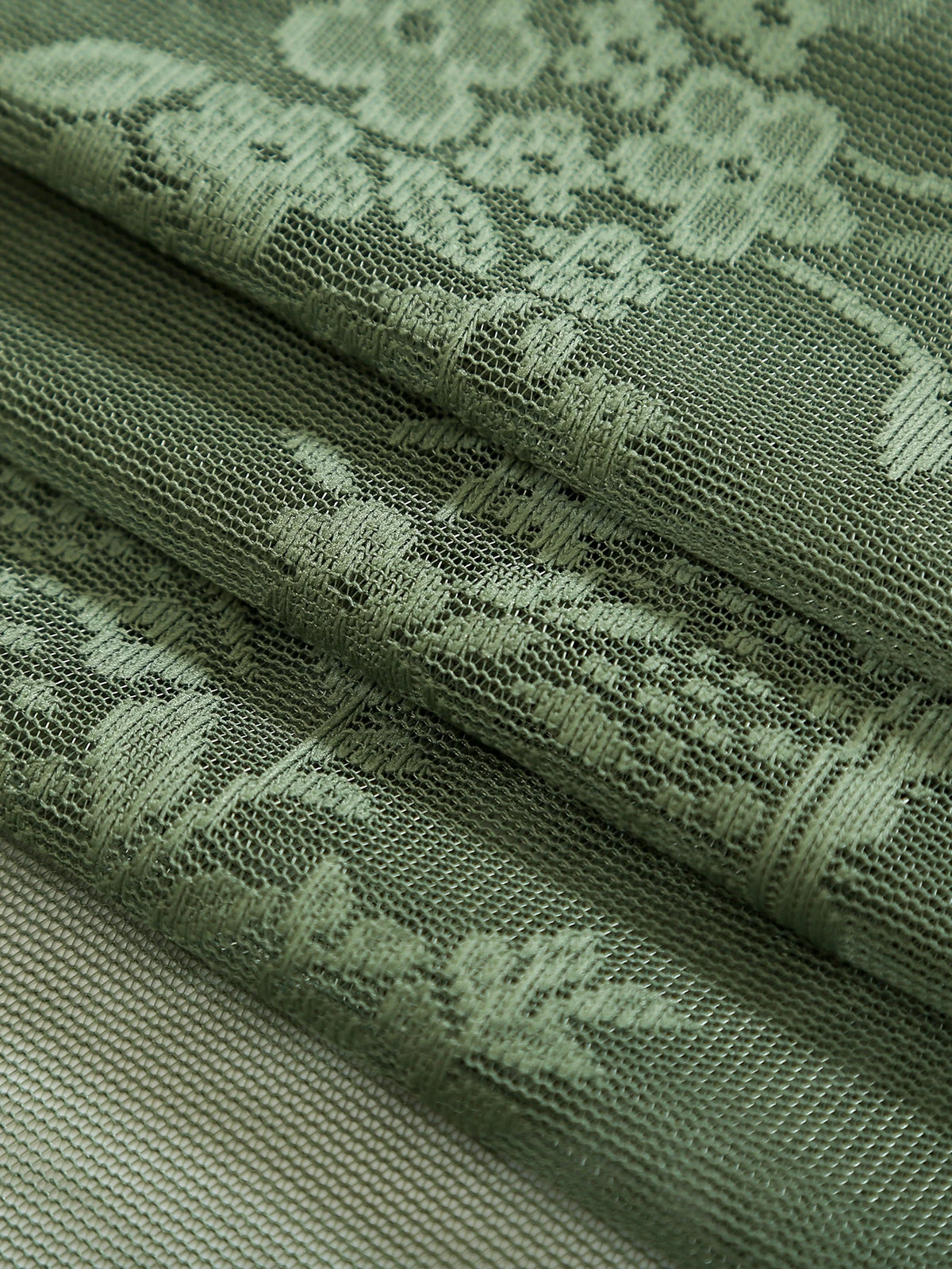 Close-up of olive green boho lace sheer curtains showing intricate floral patterns and texture.