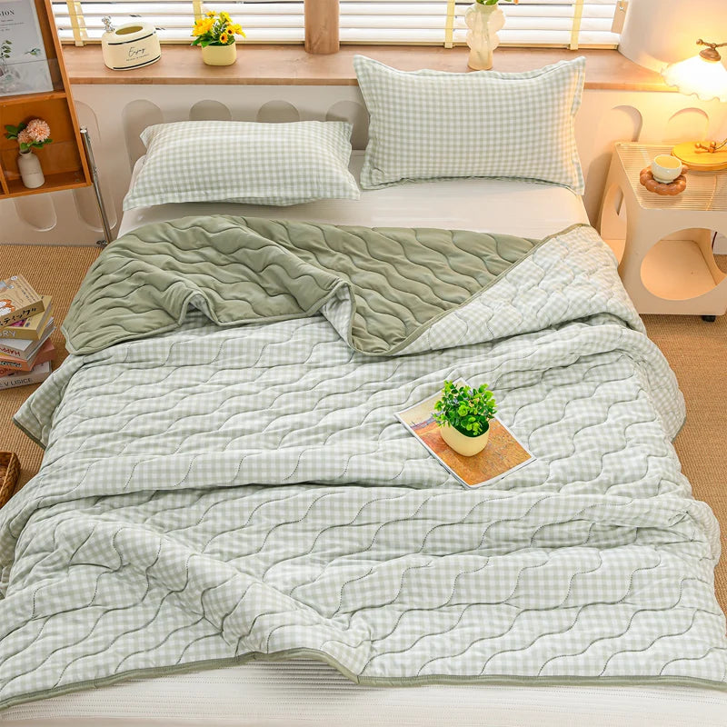 A light green quilted quilt set with a white and green plaid pattern is displayed on a bed.
