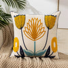 A cream-colored throw pillow cover embroidered with yellow and orange floral designs on a neutral beige textured surface.