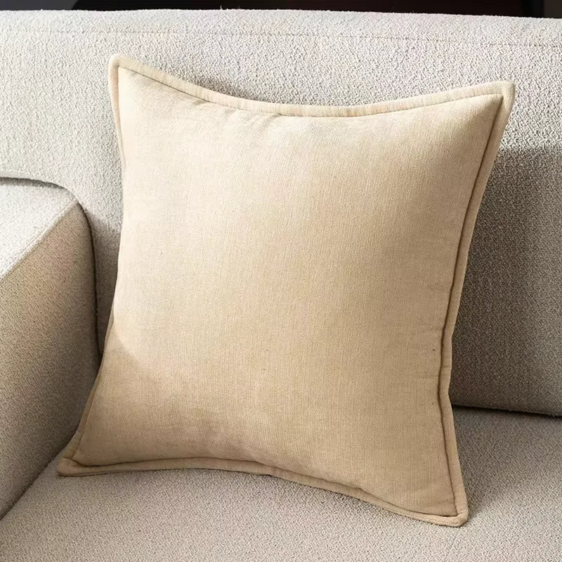 A beige chenille throw pillow resting on a light-colored sofa fabric.