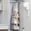 A double-sided hanging closet organizer bag with various light beige and pink bags displayed on a gray wall shelf.