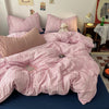 A pink gingham duvet cover set with matching pillows and a small white stuffed animal on a bed.