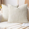 A close-up of a cream boucle texture throw pillow cover resting on a light-colored sofa.
