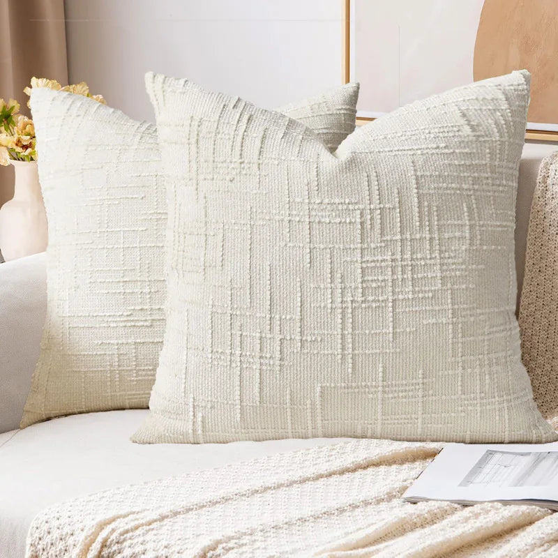 A close-up of a cream boucle texture throw pillow cover resting on a light-colored sofa.