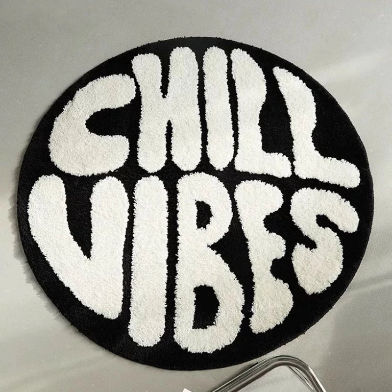 A round black floor mat with white fuzzy letters spelling out CHILL VIBES