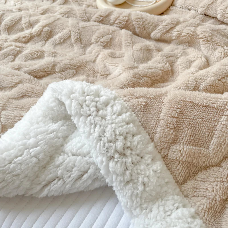 A white fluffy fleece blanket draped over a beige quilted blanket.