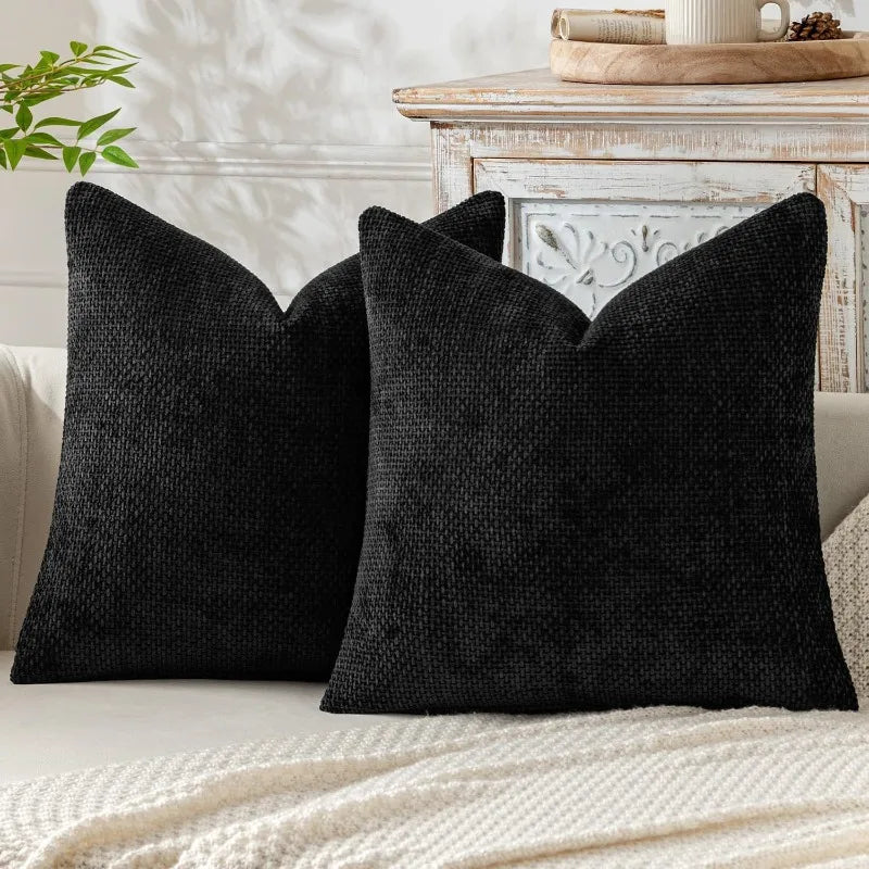 A black textured chenille pillow cover with a minimalist design resting on a light-colored surface.