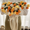 A hand knitted floral rose bouquet arrangement featuring orange yellow and white flowers displayed against a white shirt and 