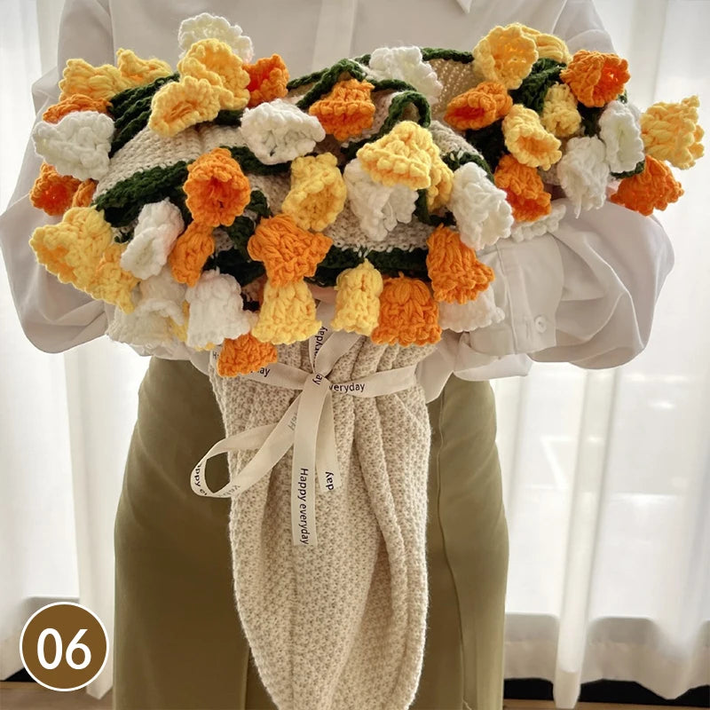A hand knitted floral rose bouquet arrangement featuring orange yellow and white flowers displayed against a white shirt and 