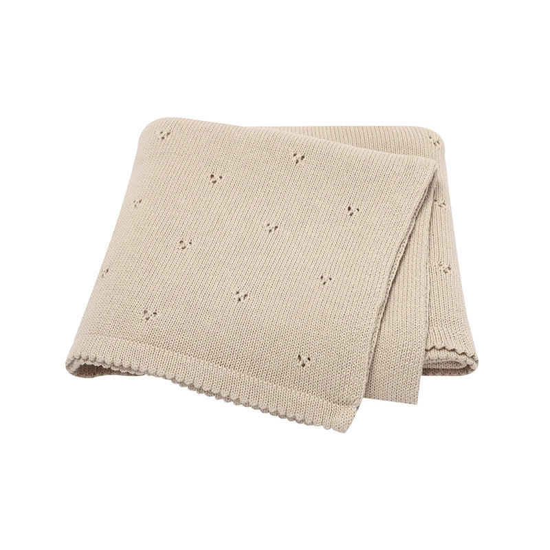 A beige knitted baby blanket folded next to another similar blanket.