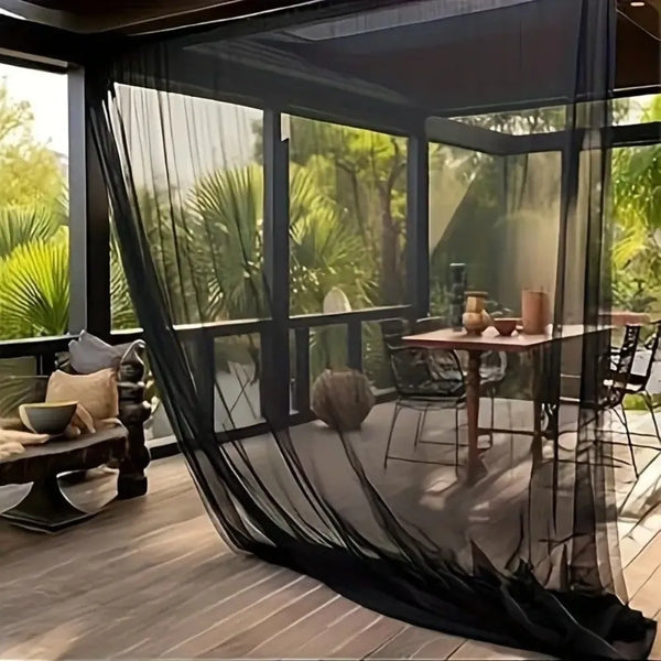 A black mesh netting is draped over a large glass window, obscuring a lush green garden view.