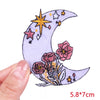 A purple crescent moon embroidered with yellow stars and pink flowers on a fabric patch.
