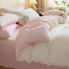 A pink and white duvet cover set featuring soft polyester bedding and pillows with a small stuffed animal.
