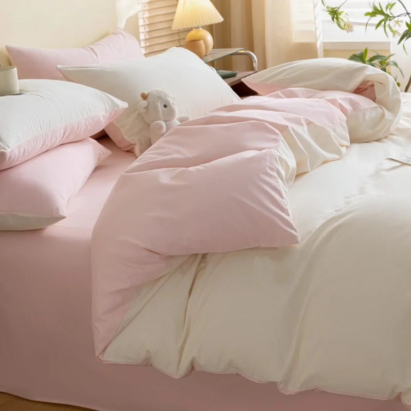 A pink and white duvet cover set featuring soft polyester bedding and pillows with a small stuffed animal.