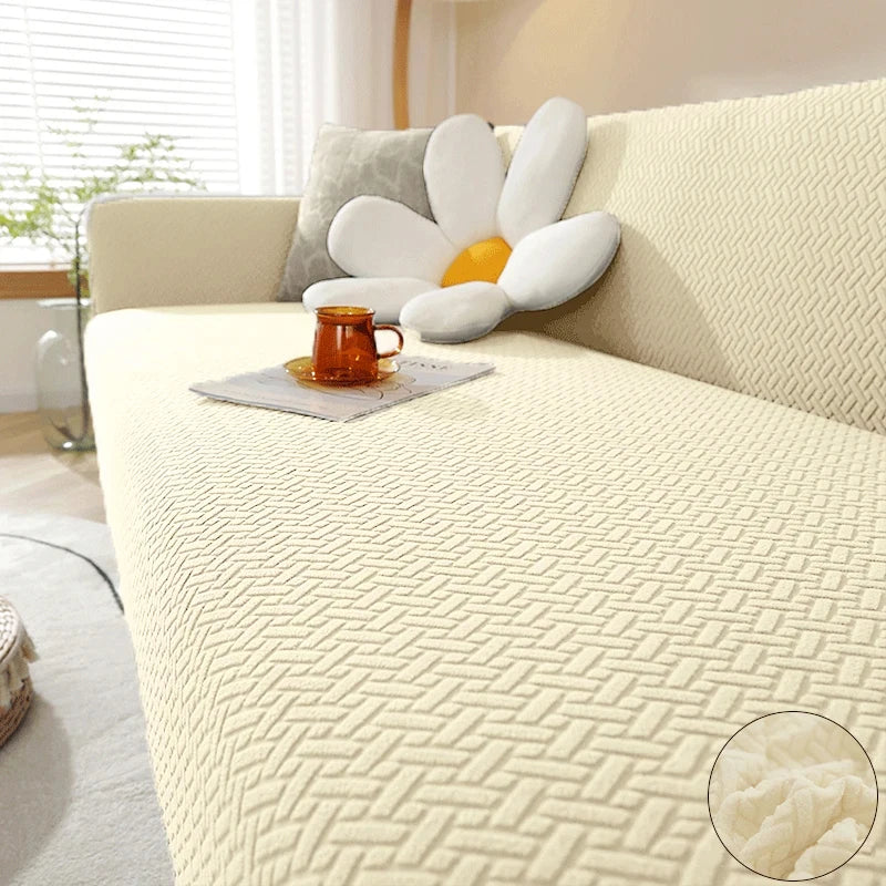 A thick cream jacquard sofa cover featuring a white flower cushion and an orange mug on a light-colored sofa.