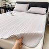 A white cooling ice silk bed pad is shown on a bed, with a hand touching the fabric.