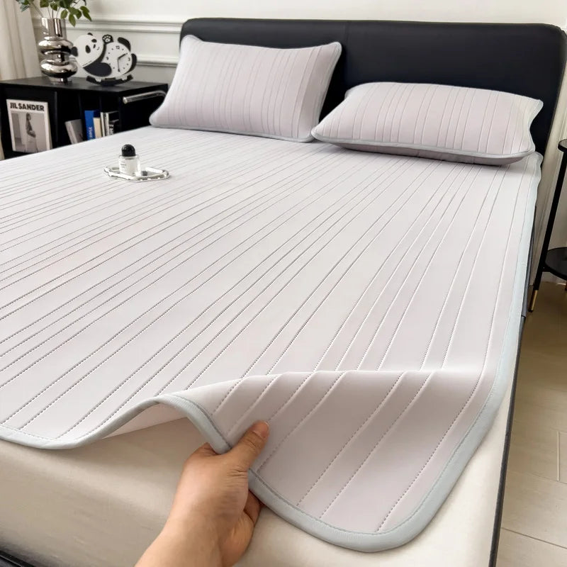 A white cooling ice silk bed pad is shown on a bed, with a hand touching the fabric.