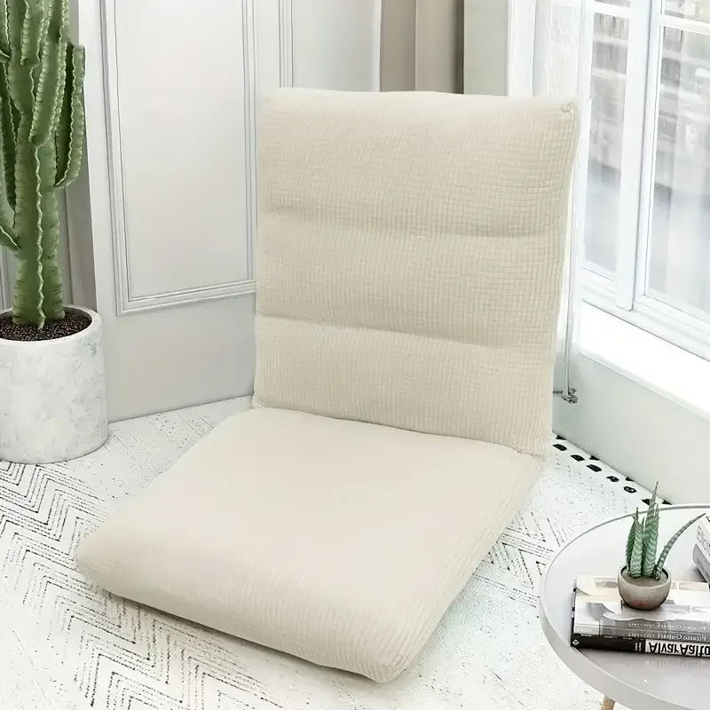 A beige folding tatami seat cover placed on a white floor, next to a potted cactus.