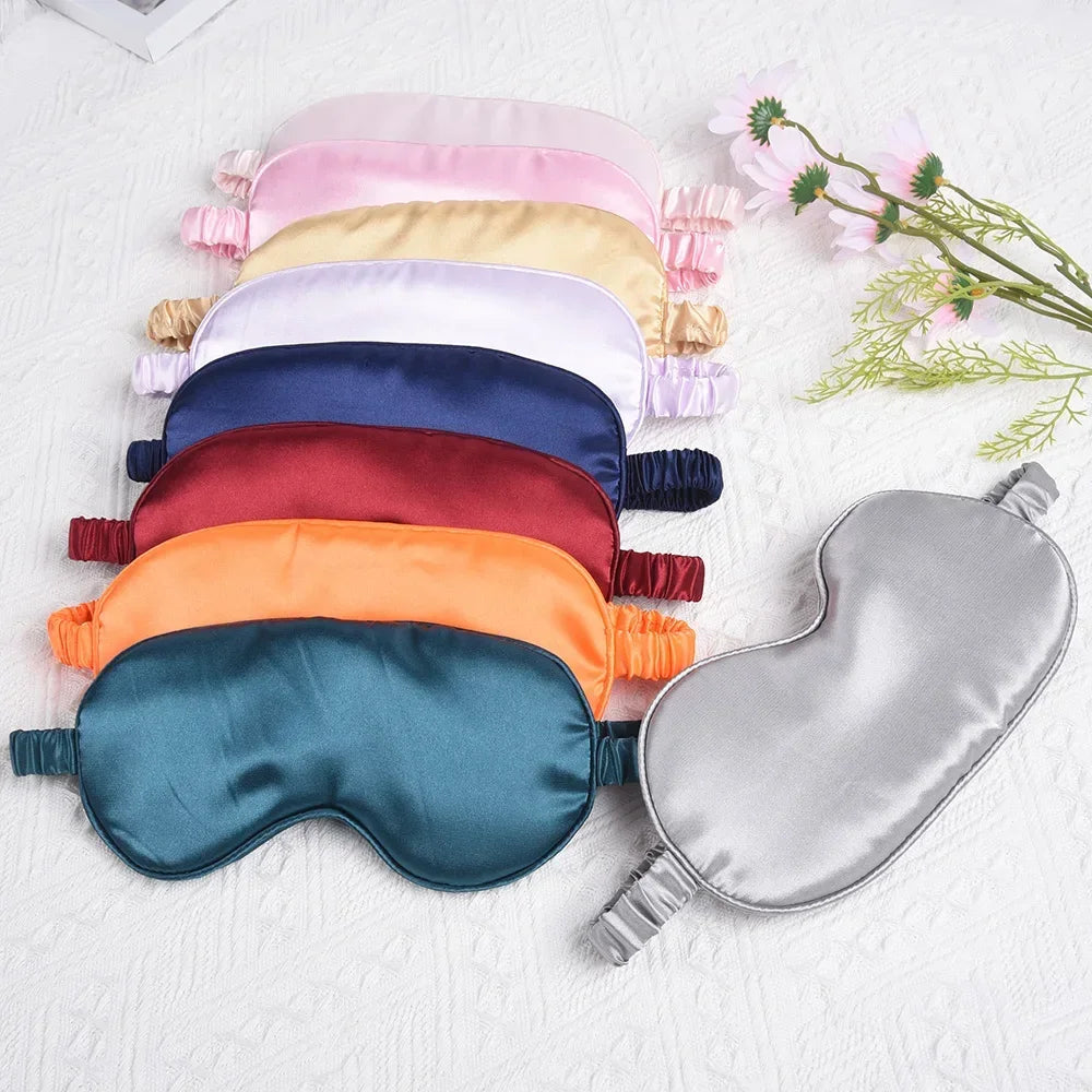 A collection of silk sleep masks in various pastel and jewel tones laid out on a white surface.