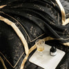 Black luxury lyocell eucalyptus bedding set draped elegantly with gold trim and a glass of amber liquid
