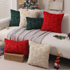 A set of seven textured corduroy throw pillow covers in shades of red, green, and cream are displayed on a white sofa.