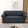 A dark gray stretch knit sofa cover featuring a bubble lattice texture placed on a light rug.