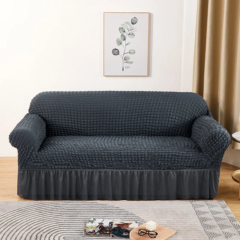 A dark gray stretch knit sofa cover featuring a bubble lattice texture placed on a light rug.