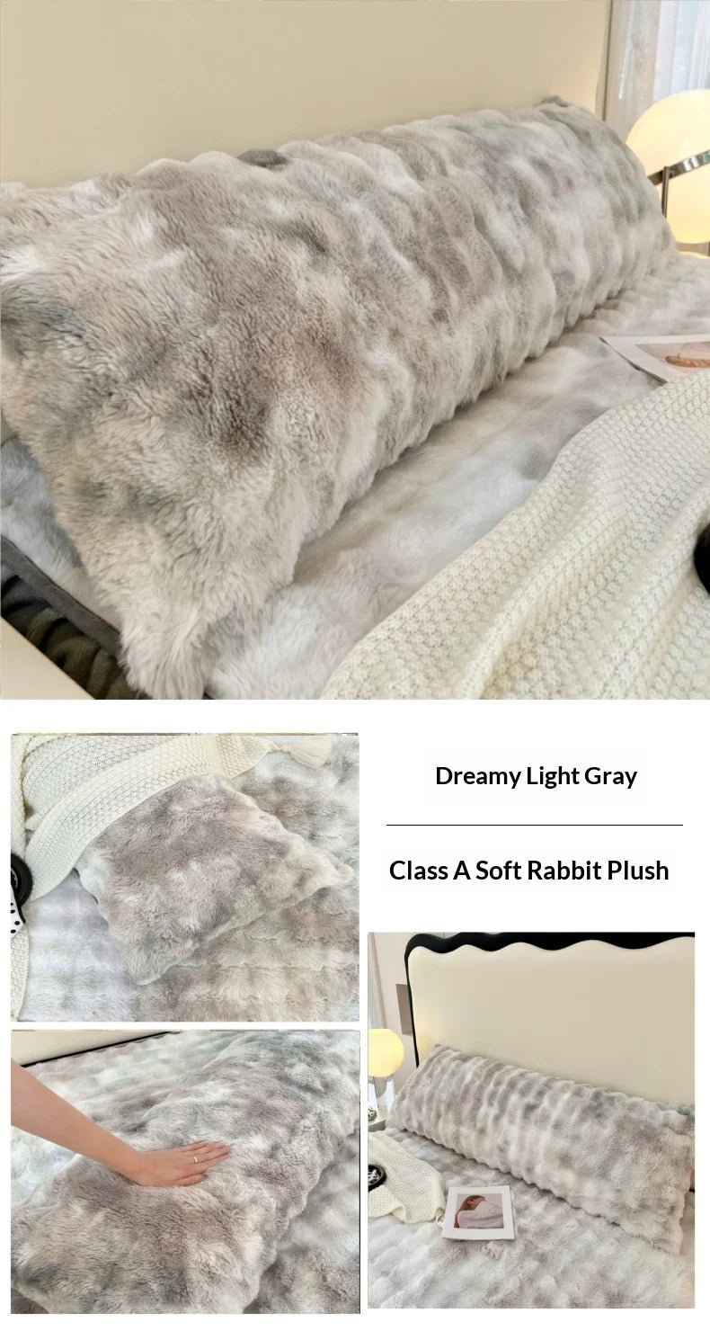 A fluffy light gray rabbit plush long pillowcase displayed on a bed with a white knitted blanket.
