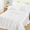 White ruffled satin pillowcase set with silky envelope closure covers on a bed