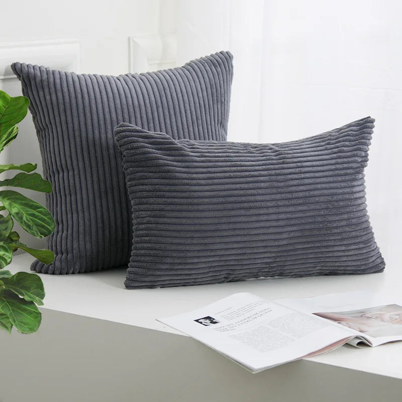 A dark gray corduroy striped throw pillow cover resting on a white surface.
