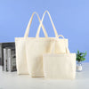 Three natural canvas tote bags are displayed against a light blue background.
