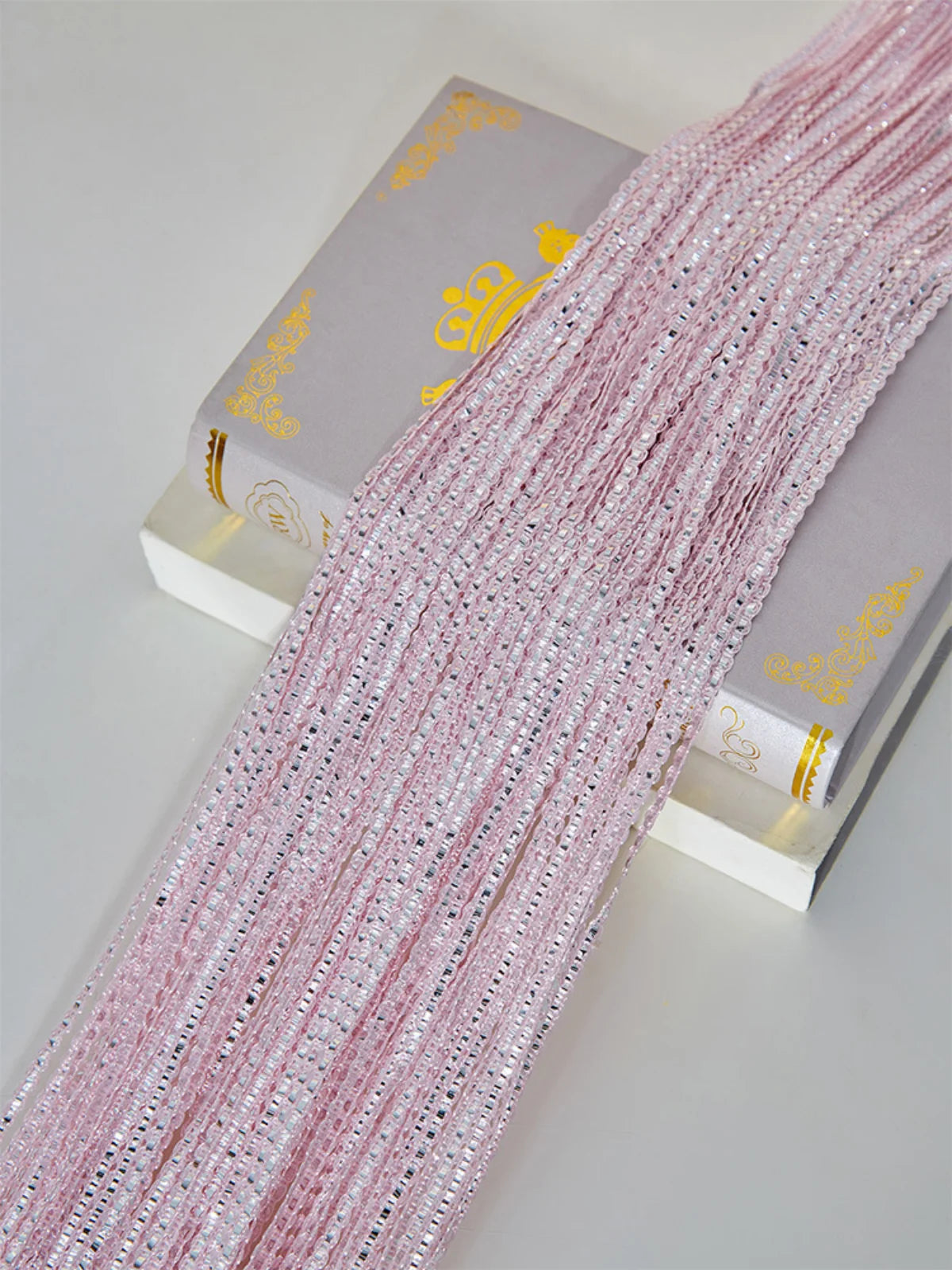 Pink decorative door string curtains displayed next to a box.