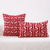Two red and white geometric patterned throw pillows resting on a white textured fabric surface.