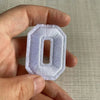 A hand holds a white, custom-shaped number patch with the numeral zero.
