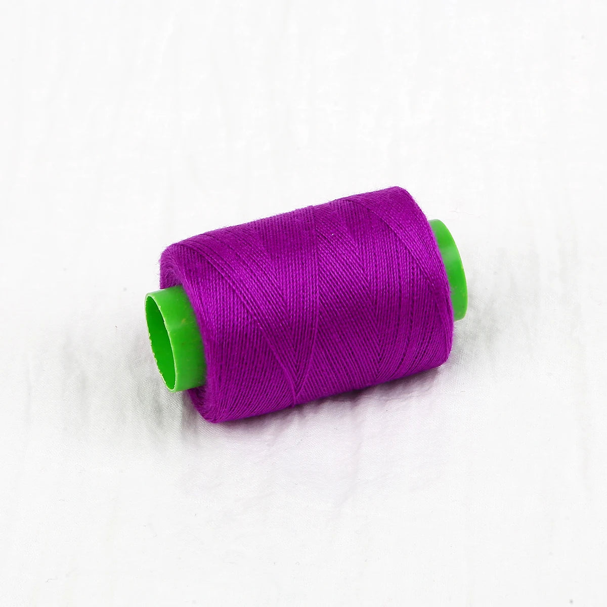 A roll of vibrant purple handmade sewing threads with a green core.