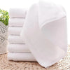 A stack of white cotton face towels is shown on a woven mat.