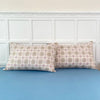 A set of two plaid patterned pillow covers resting on a light blue bed.