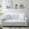 A white elegant faux silk sofa cover displayed on a light gray wall with framed art.