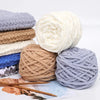 A pile of soft white, beige, and gray chenille knitting yarn balls with wooden chopsticks in the foreground.
