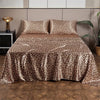 Leopard print satin bed sheet set displayed on a bed with modern decor.
