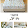 Floral printed cotton fitted sheet with delicate pink and green flowers on a bed.