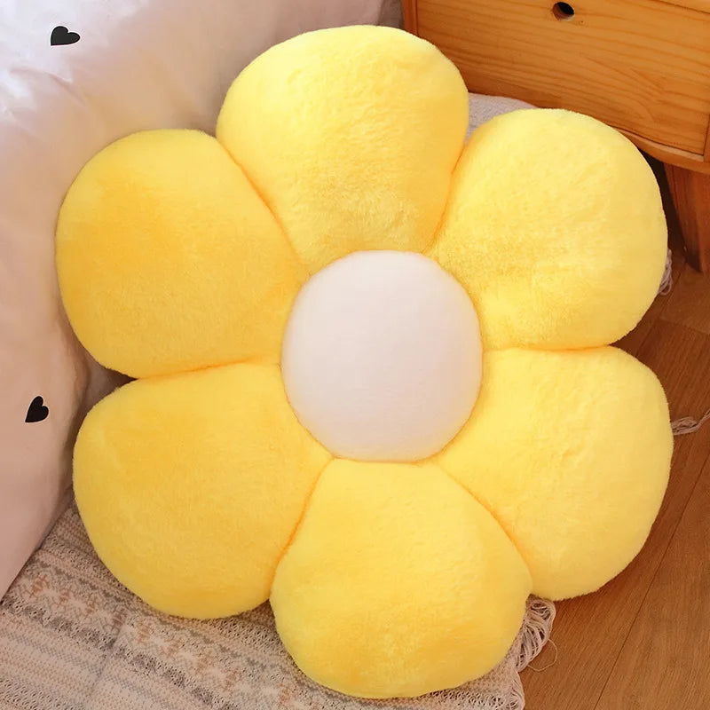 A bright yellow sunflower plush flower cushion with a white center resting on a light fabric.