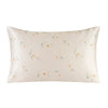 A square silk pillowcase with a pale beige background and a delicate floral print featuring small orange and green leaves.