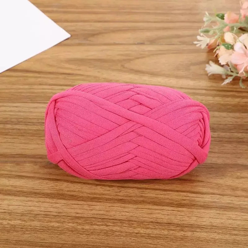 A pink flat thread yarn skein lying on a wooden surface.